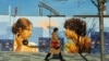 A woman walks past a fence with a mural on the street in Moscow