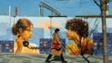 A woman walks past a fence with a mural on the street in Moscow