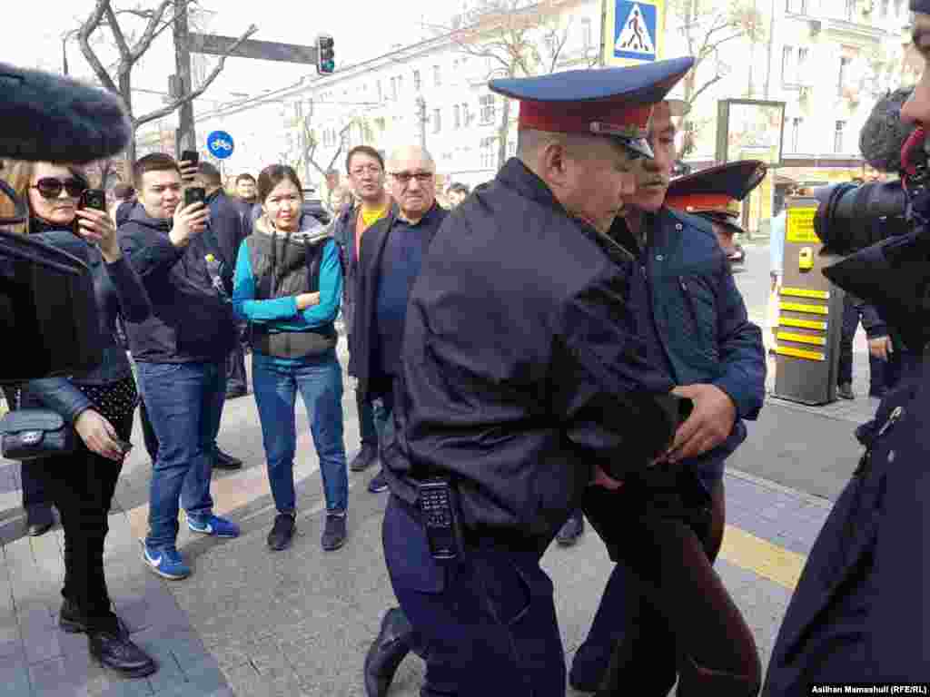 Полицейские забирают человека, заявлявшего, что он "пришел на празднование Наурыза". Алматы, 22 марта 2019 года. 