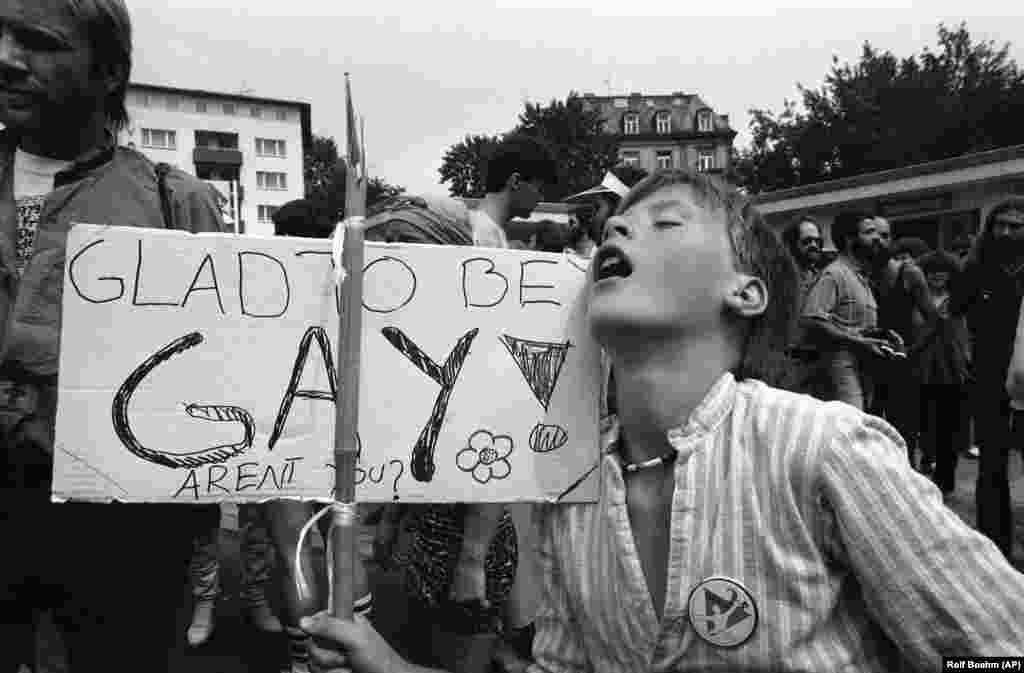 Un manifestant olandez în vârstă de 30 de ani afișează o pancartă pe care scrie: „Mă bucur că sunt gay” în timpul unui marș la Frankfurt, Germania, pe 28 iulie 1979, care a încheiat săptămâna homosexualilor. Sute de oameni s-au întâlnit pentru o săptămână de filme, teatru, concerte rock și ateliere despre drepturile homosexualilor. Homosexualii și lesbienele din Germania și din alte țări au cerut încetarea discriminării împotriva homosexualității.