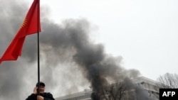 A Kyrgyz protester waves the national flag near the main government building during an antigovernment protest in Bishkek on April 7, 2010.