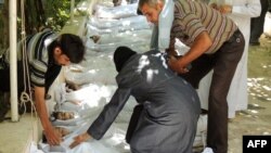 A Syrian woman mourns over a child's body wrapped in a shroud laid out in a line on the ground with other victims that Syrian rebels claim were killed in a gas attack by pro-government forces near Damascus on August 21.