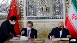 Iranian Foreign Minister Mohammad Javad Zarif (right) and his Chinese counterpart, Wang Yi, sign a cooperation agreement in Tehran on March 27.