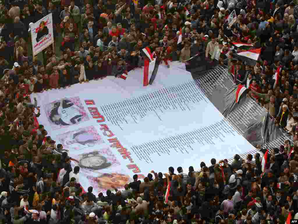 Antigovernment protesters carry a huge banner with the names and pictures of victims killed during the protests.