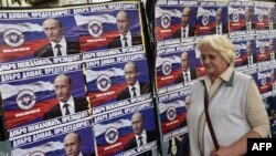 A woman walks past posters showing Russian President Vladimir Putin reading "Welcome, President" in Belgrade on October 15.
