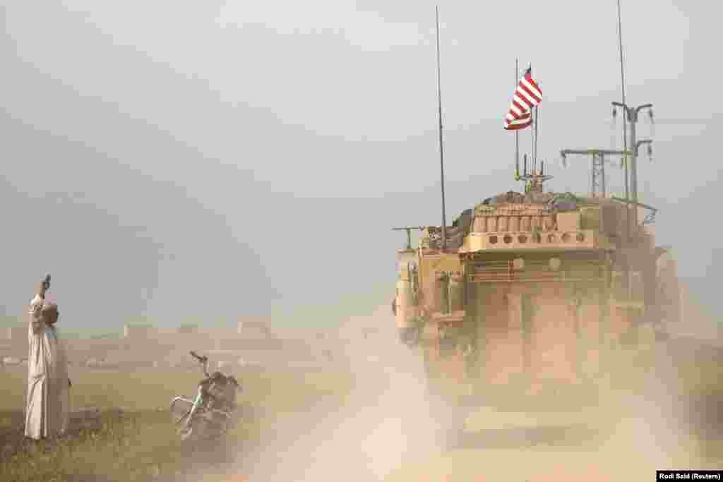 A local flashes a "V for victory" sign at U.S. military vehicles near Al-Darbasiyah. According to the U.S. Defense Department, the coalition has recaptured around 90 percent of the territory once held by IS in Syria. 