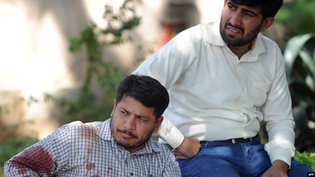 An injured United Nations employee rests outside his agency's office after a suicide blast in Islamabad.