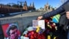 Un bărbat pune un bilet pe care scrie „Nu războiului!” în locul unde liderul opoziției Boris Nemțov a fost împușcat mortal, în apropierea Kremlinului. Imagine din 27 februarie 2022, la a șaptea aniversare a asasinării opozantului rus.