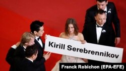 Russian actress Irina Starshenbaum (center) and other cast members hold a sign with the name of Russian director Kirill Serebrennikov as they arrive for the screening of his film Leto in Cannes.