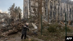A woman cleans debris near a heavily damaged building, which was hit in a missile attack on the city of Izyum in eastern Ukraine on February 4.