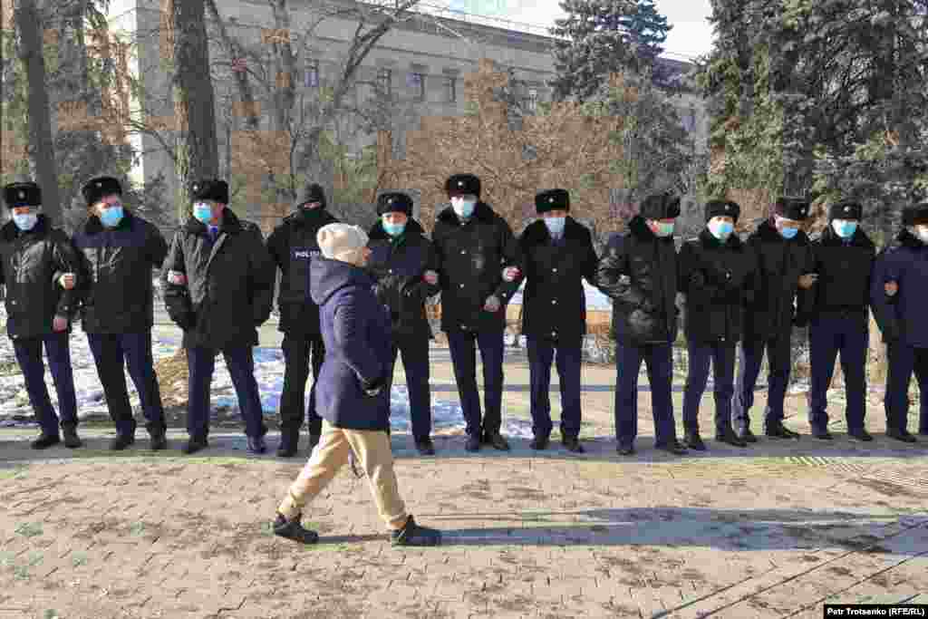 A participant of the protest rally passes a line of police officers in Almaty.