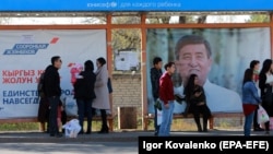 People wait for a bus in front of election campaign posters at a bus stop in the Kyrgyz capital, Bishkek. The country goes to the polls to elect a new president on October 15. 