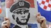 In Zagreb, a woman holds a newspaper with a portrait of General Ante Gotovina over the word "hero" as she watches the verdict in The Hague.